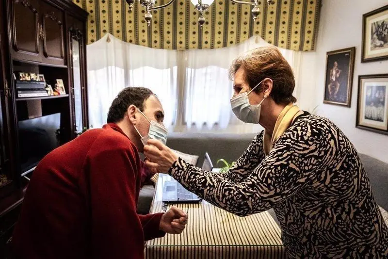  Archivo - Una mujer ayuda a su hijo con discapacidad a colocarse la mascarilla. - ROBERTO PALOMO - Archivo 
