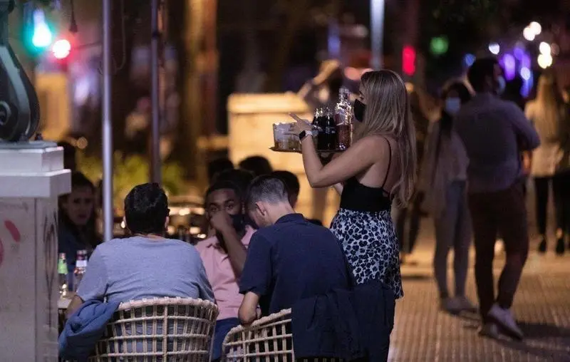  na camarera atiende a varias personas en la terraza de un bar 