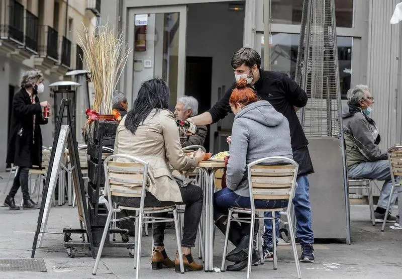  Un camarero atiende a dos clientas en una terraza el primer d&iacute;a de la apertura de la hosteler&iacute;a. EP 