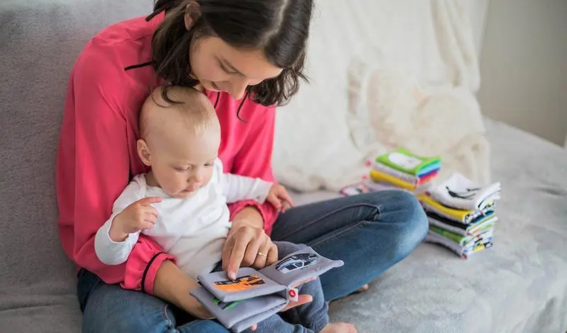 <p> Una madre con su beb&eacute; mirando un libro infantil. </p>