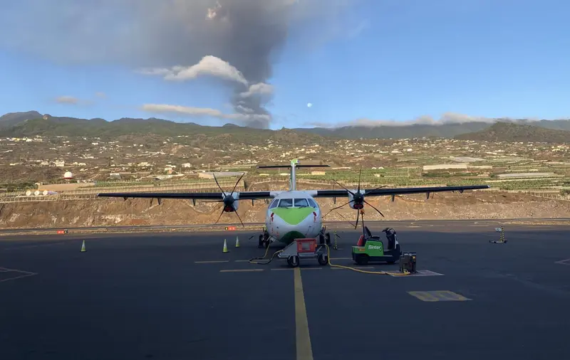 <p> Un avi&oacute;n de Binter en la pista del aeropuerto de La Palma, con el volc&aacute;n en erupci&oacute;n al fondo - BINTER </p>