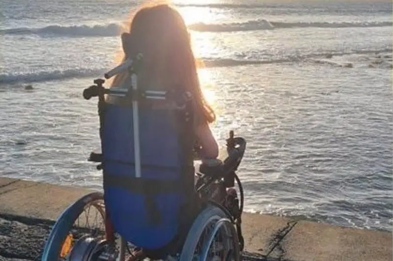 <p> Una joven en silla de ruedas mirando al mar. - CHANGE.ORG </p>