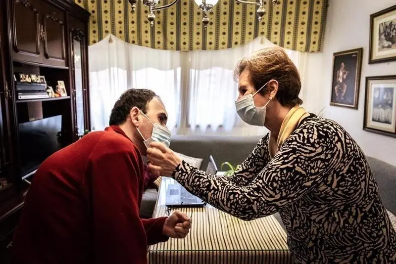 <p> Archivo - Una mujer ayuda a su hijo con discapacidad a colocarse la mascarilla. - ROBERTO PALOMO - Archivo </p>