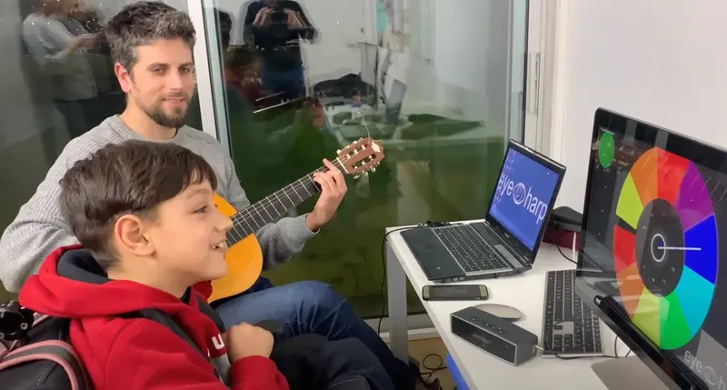<p> El profesor ayuda a un ni&ntilde;o con discapacidad a hacer m&uacute;sica </p>