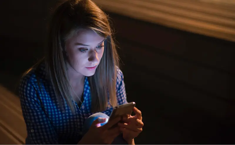 <p> Una joven lee mensajes en su tel&eacute;fono m&oacute;vil. </p>