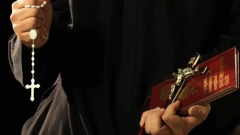 <p> Cura con una biblia y un rosario </p>