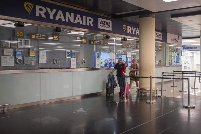 <p> Dos personas pasan junto a una ventanilla de Ryanair en el Aeropuerto Josep Tarradellas Barcelona </p>