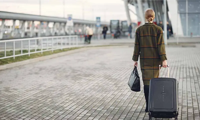  Una mujer camina con su maleta camino del aeropuerto. 