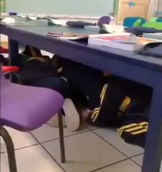  Los alumnos resguardados bajo las mesas 