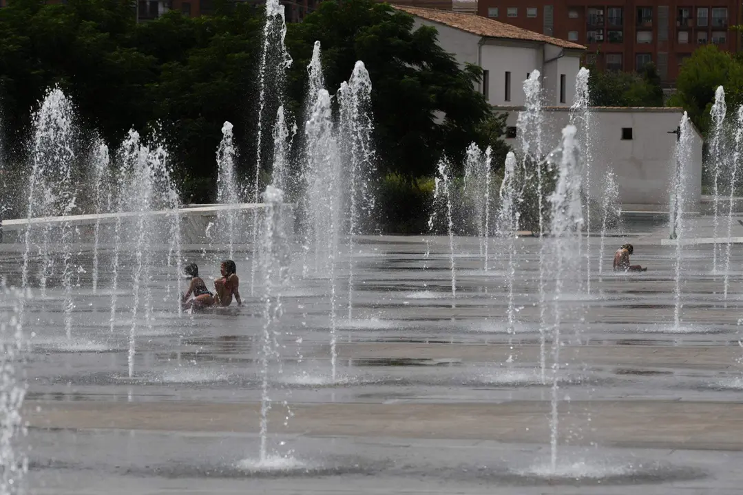  Varios ni&ntilde;os se refrescan en una fuente 