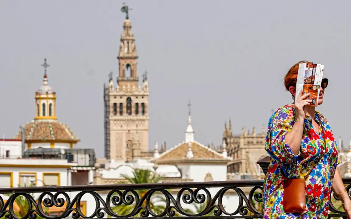  Una persona paseando por el Puente de Triana se protege la cara el d&iacute;a en que la capital est&aacute; en alerta naranja por el calor , a 19 de julio del 2023. - Eduardo Briones - Europa Press 
