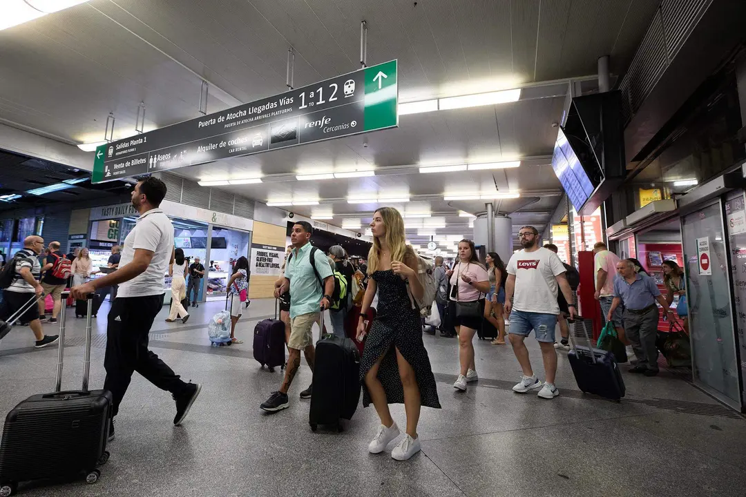  Un grupo de personas con maletas camina por uno de los pasillos de la estaci&oacute;n de Atocha-Almudena Grandes con motivo de la operaci&oacute;n salida de inicios de agosto, en Madrid 
