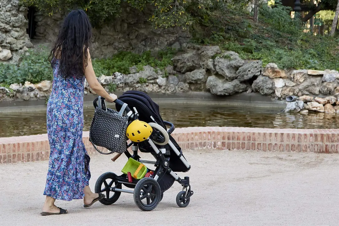  Una persona pasea con un carrito de beb&eacute; en el parque de El Retiro 