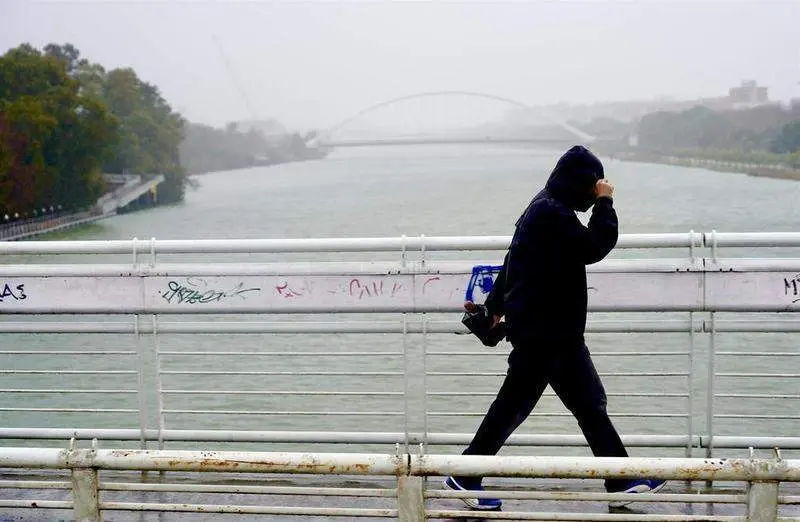  Imagen de archivo de un persona protegi&eacute;ndose de la lluvia y el viento en Sevilla 