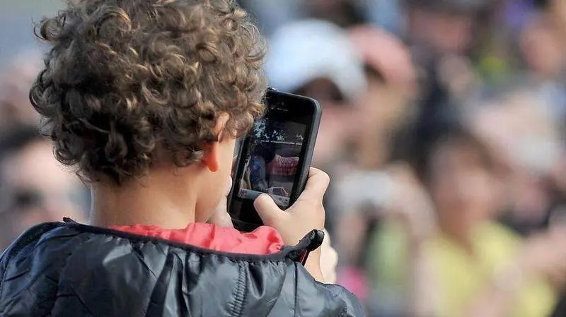  Ni&ntilde;o con un tel&eacute;fono m&oacute;vil en el recreo. 