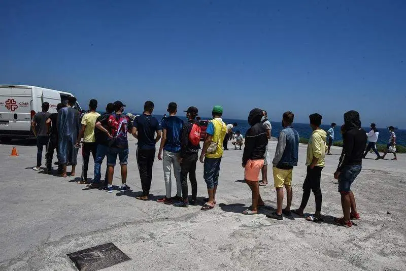  Varios migrantes que entraron a Ceuta hacen cola para recibir alimentos de C&aacute;ritas Diocesana |  Europa Press 