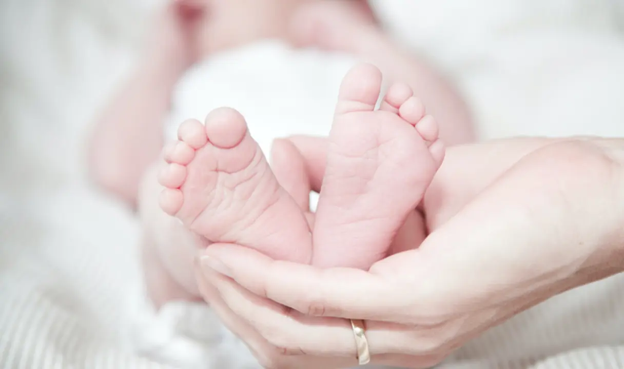  Las manos de una madre sostienen los pies de su beb&eacute;. 