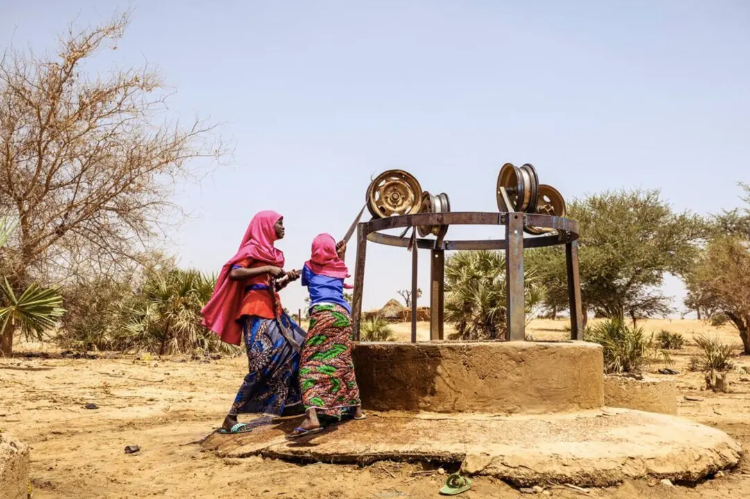  Mahana, 9, and her sister Firdaoussou, 12, get water from a well.The well has only had water for 4 days and is polluted with frogs and garbage. When this well runs dry, they will need to go further. - JON WARREN | EP 