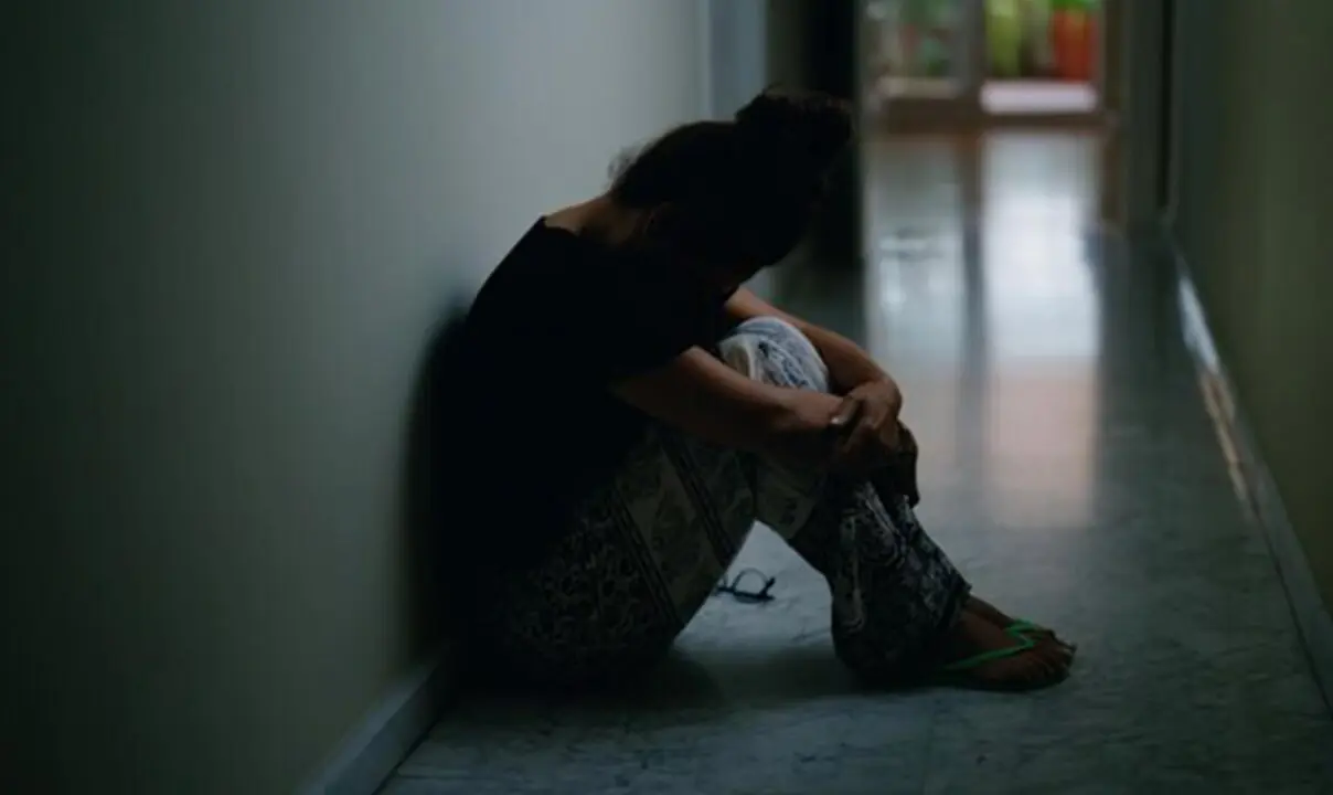  Una joven expresa su malestar sentada en un pasillo. 