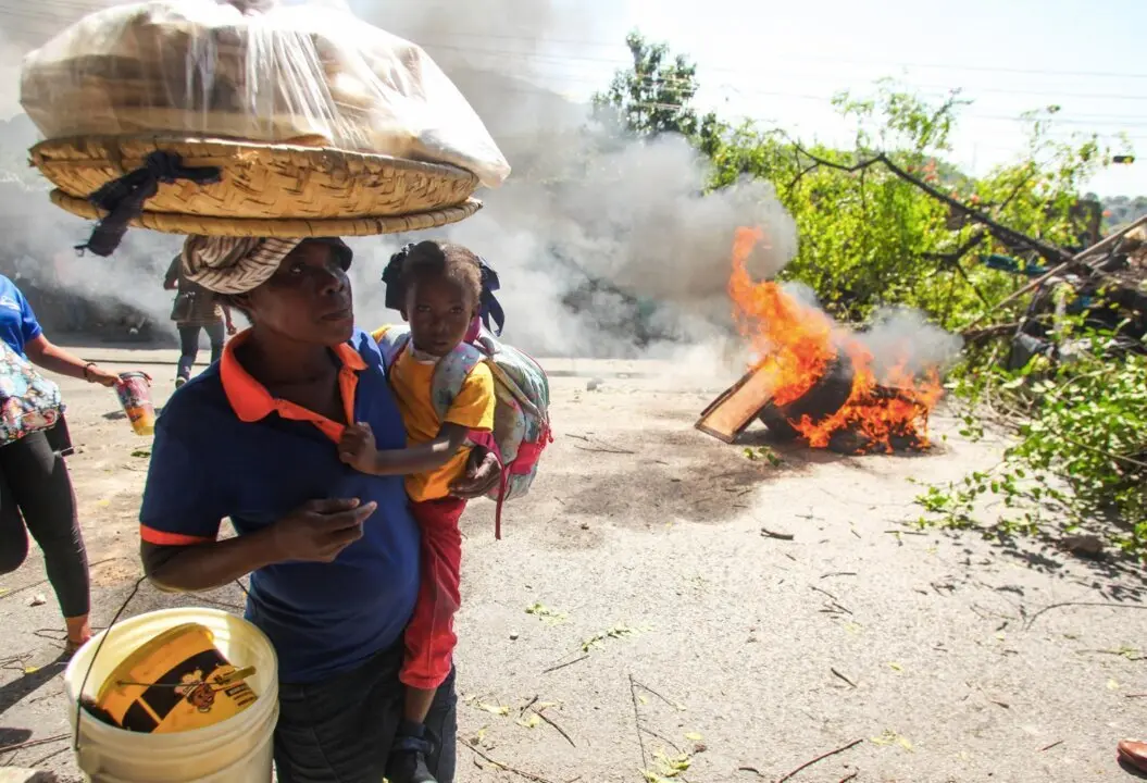  Una mujer con una ni&ntilde;a pasan junto a una barricada en llamas, en Puerto Pr&iacute;ncipe. - Patrice Noel/ZUMA Press Wire/dpa | EP 
