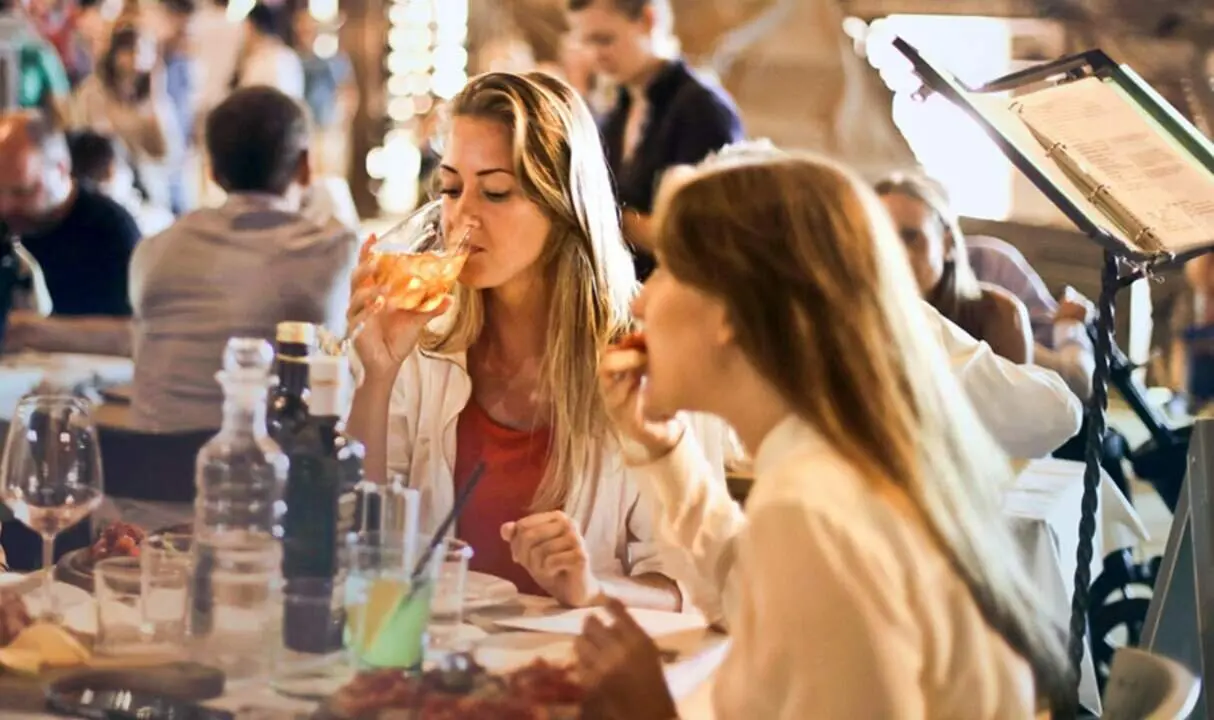  Dos j&oacute;venes almuerzan en un restaurante. 