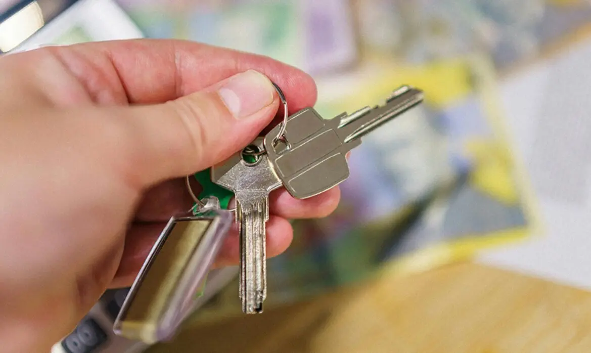  Una persona sostiene las llaves de una vivienda. 