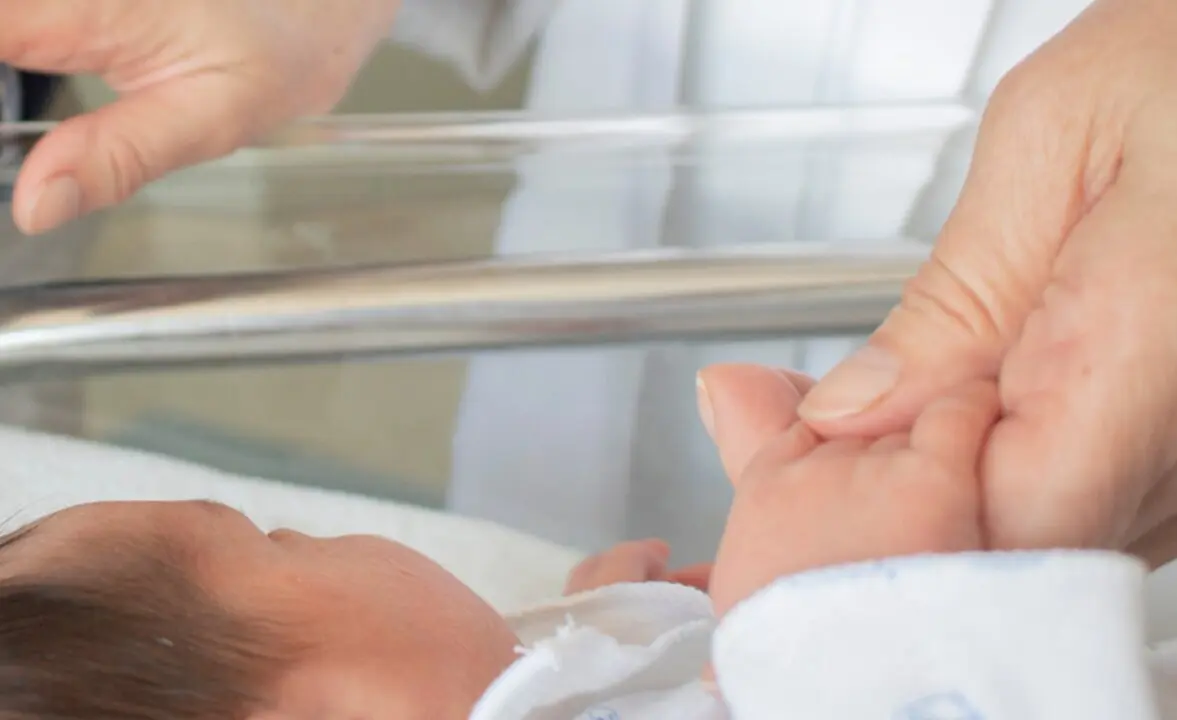  Una enfermera toma la mano a un reci&eacute;n nacido. 