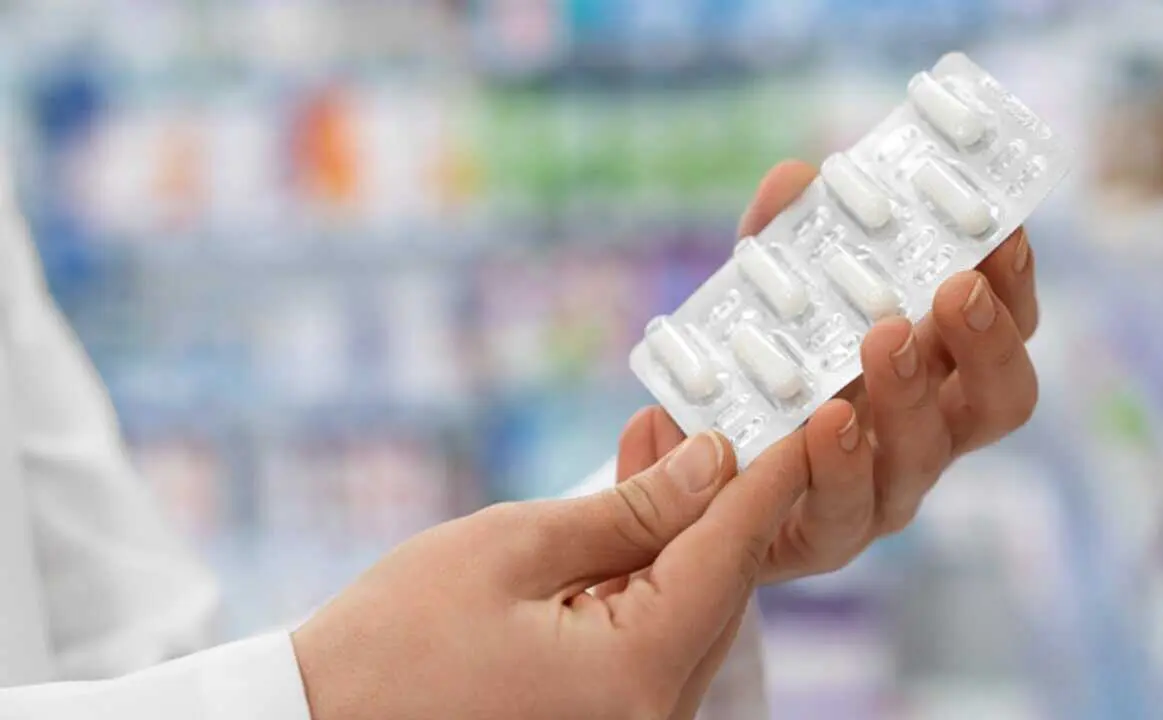  Una mujer muestra una tableta de pastillas. 