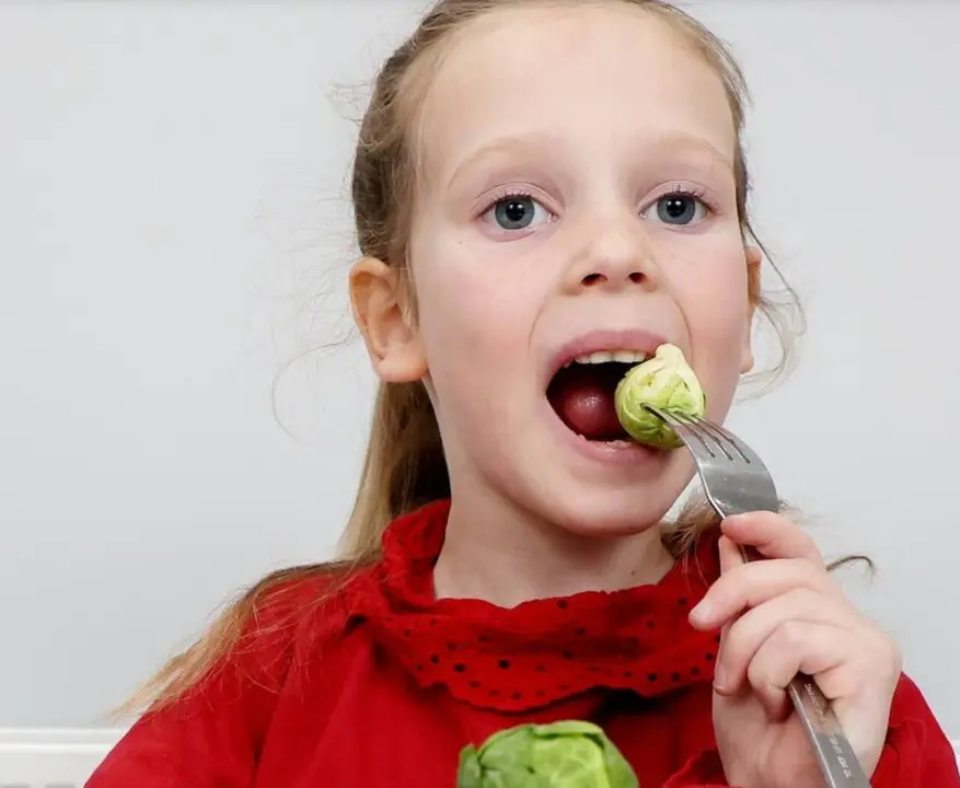 Emie comiendo las coles de Bruselas