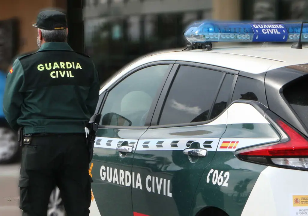Archivo - Un agente de la Guardia Civil, de espaldas, de pie junto a un veh&iacute;culo oficial.