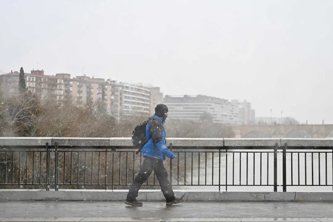 Archivo - Una persona camina por la calle bajo la nieve, a 19 de enero de 2024, en Zaragoza, Arag&oacute;n (Espa&ntilde;a). 