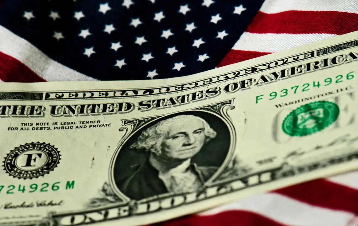Archivo - FILED - 14 July 2011, Dresden: A US One Dollar is pictured on a US flag. Photo: Arno Burgi/dpa-Zentralbild/dpa