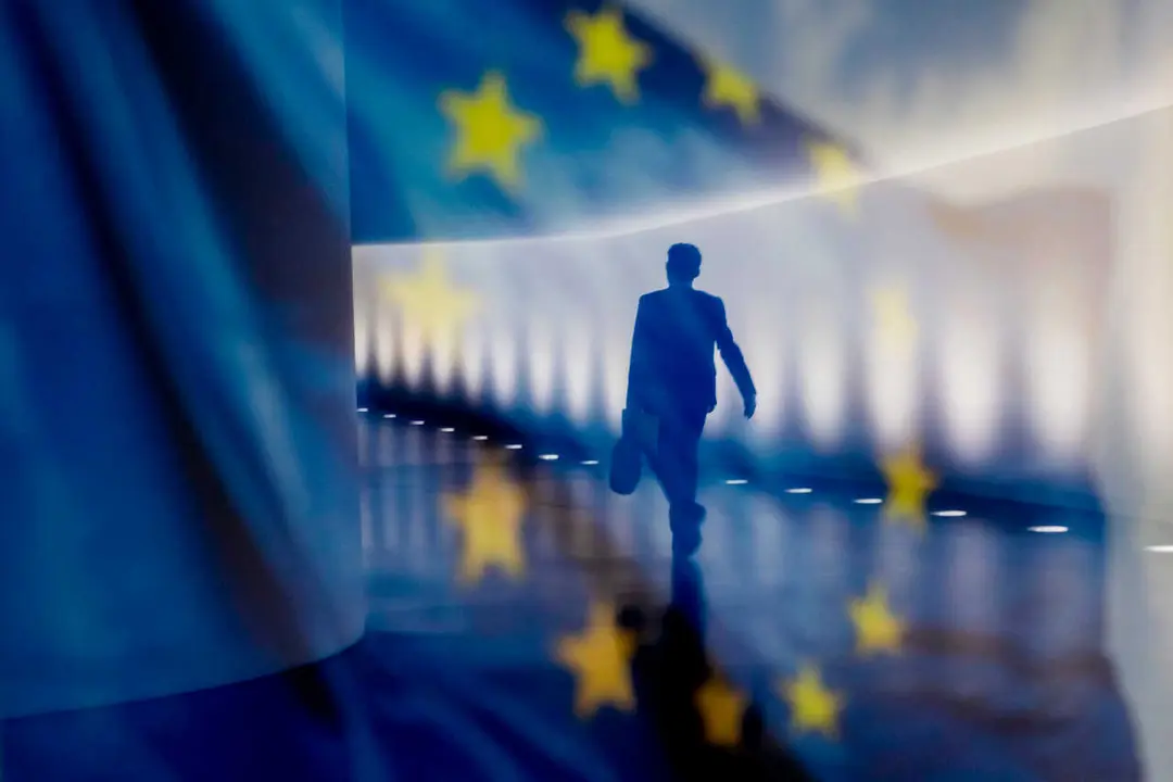 Archivo - Reflejo de una persona junto a una bandera de la Uni&oacute;n Europea (UE).