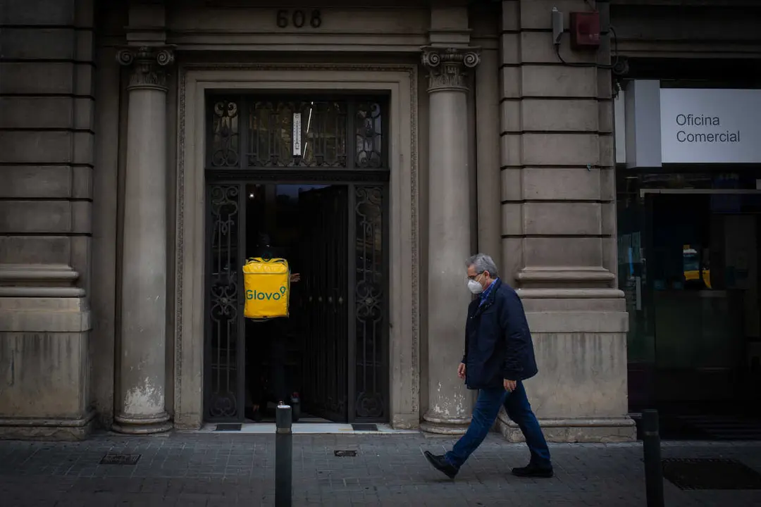 Archivo - Un trabajador de Glovo entra en un portal 