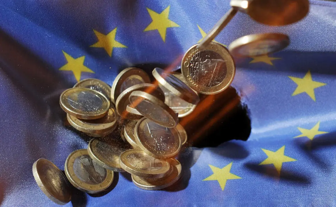 Archivo - FILED - 04 July 2011, Baden-Wuerttemberg, Karlsruhe: One euro coins will fall onto an EU&nbsp;flag. The European Union's gross domestic product shrank 3.5 per cent in the first three months of the year, according to a first estimate from Eurostat, wh