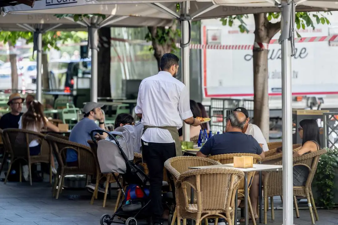 Archivo - Un camarero atendiendo la terraza de un bar en la temporada de verano