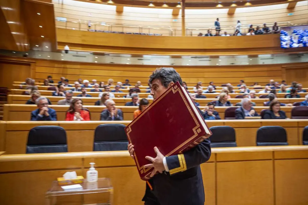 Ujier del Senado retira la Constituci&oacute;n espa&ntilde;ola del sal&oacute;n del pleno despu&eacute;s del juramento de un nuevo senador. 21/10/2025.
