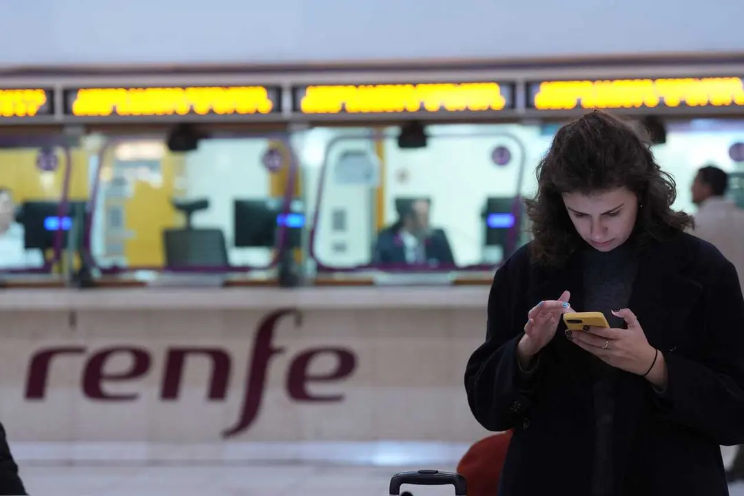 Archivo - Una persona espera en la Estaci&oacute;n de Sants ante una ventanilla de Renfe