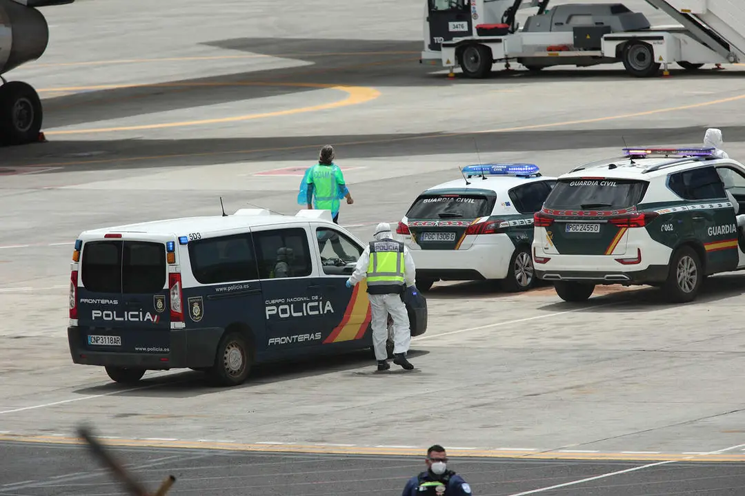 Polic&iacute;as nacionales, guardias civiles y militares de la UME vestidos con monos EPI y mascarillas coordinan a los viajeros evacuados del crucero MV Hondius, en el aeropuerto de Tenerife Sur, a 10 de mayo de 2026, en Tenerife, Islas Canarias (Espa&ntilde;a). El op