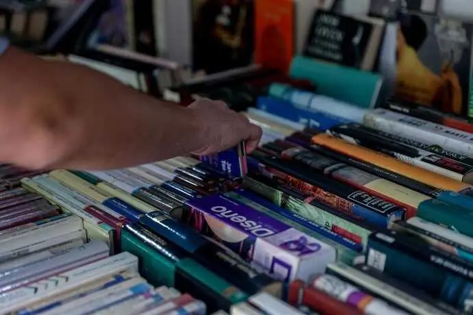 Archivo - Un joven escoge un libro en una librer&iacute;a.