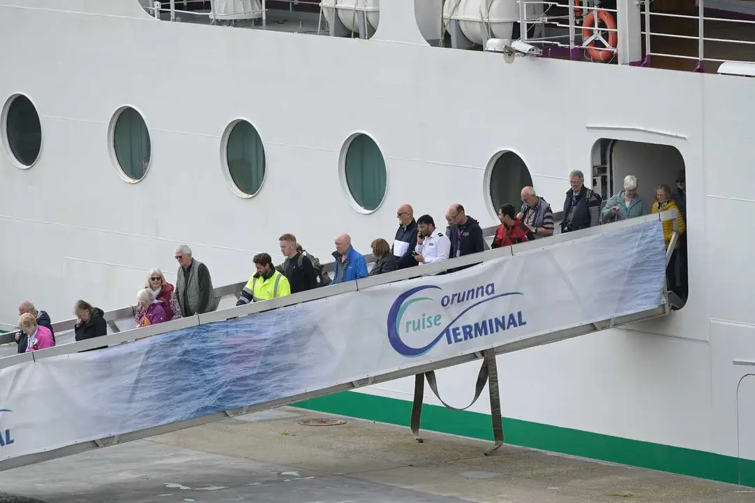 Personal sanitario (con chalecos amarillos) desembarca con pasajeros del crucero 'Ambition', aislado por un brote de gastroenteritis, durante una escala en el puerto de A Coru&ntilde;a