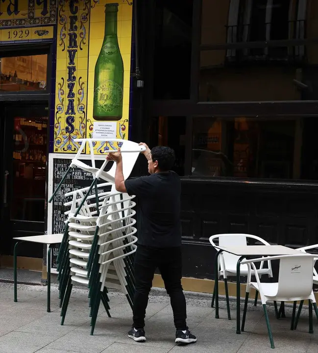 Archivo - Un camarero preparando las mesas de la terraza de un bar