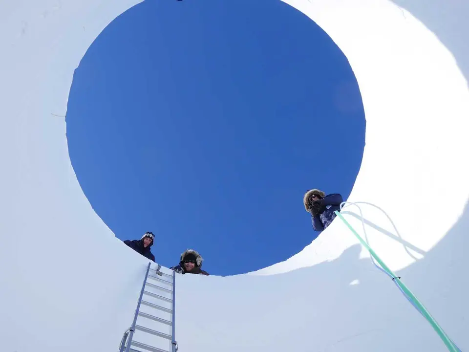 Investigadores asomados al n&uacute;cleo de hielo analizado.
