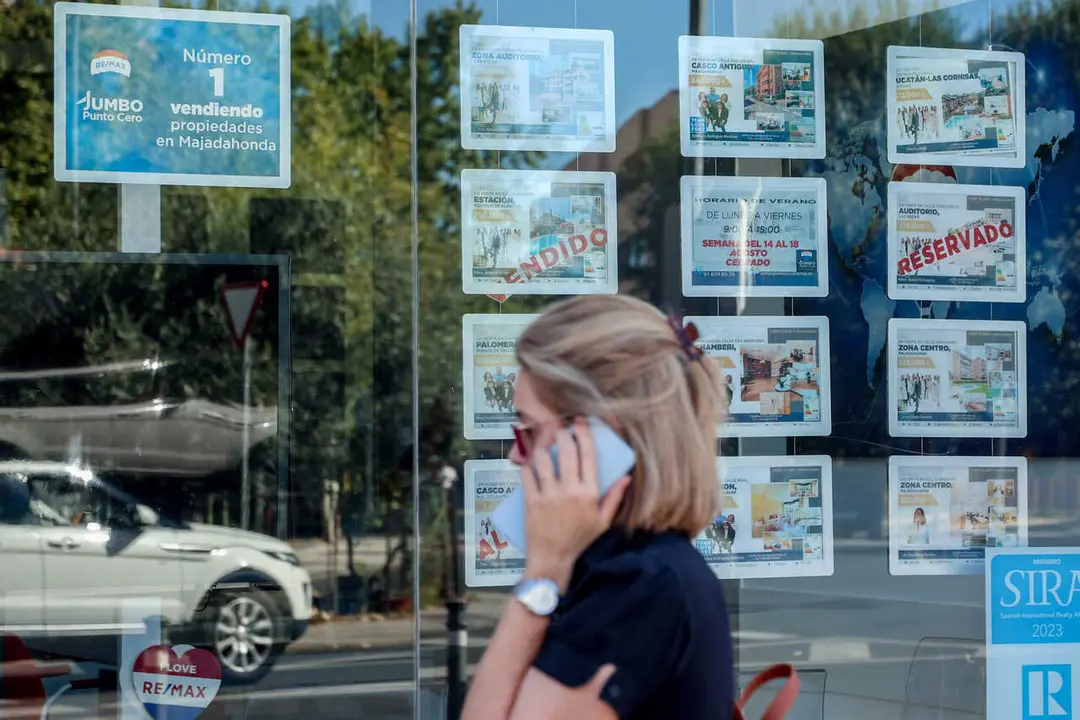Archivo - Una mujer pasa frente a un escaparate de anuncios de viviendas en Madrid (Espa&ntilde;a)