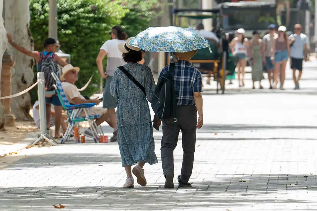 Archivo - Unos turistas pasean por la ciudad resguardados por un paraguas, a 19 de julio de 2024, en Sevilla, Andaluc&iacute;a (Espa&ntilde;a). La primera ola de calor del verano pone en alerta a Sevilla por altas temperaturas, tanto en la campi&ntilde;a como en la sierra nor