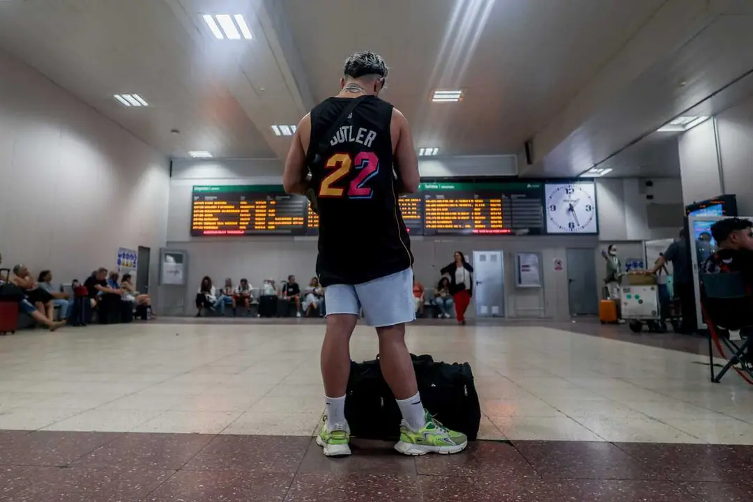 Archivo - Un joven junto a su maleta frente al panel de salidas en la estaci&oacute;n de tren de Chamart&iacute;n