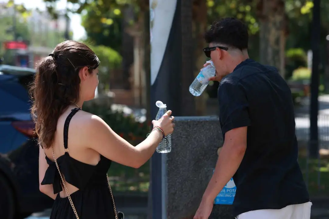 Una pareja bebe agua durante la ola de calor. A 05 de julio de 2026, en Sevilla (Andaluc&iacute;a, Espa&ntilde;a). Andaluc&iacute;a se sit&uacute;a como la comunidad que registra las temperaturas m&aacute;s altas durante la segunda ola de calor del verano, declarada el pasado viernes. En l