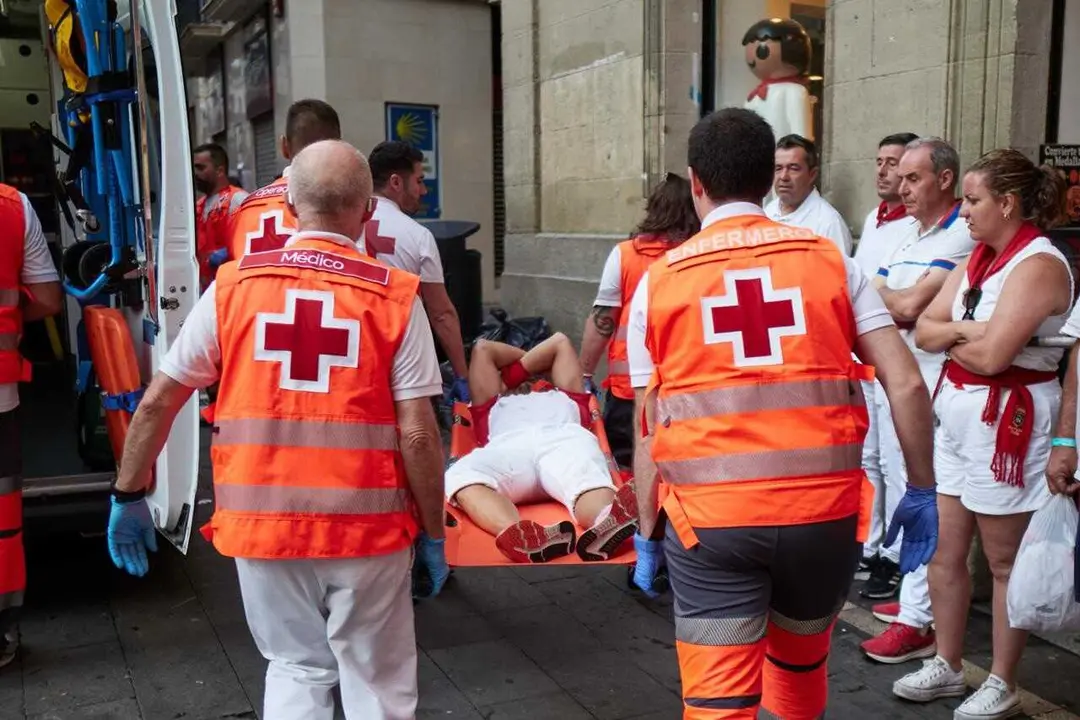 Voluntarios de Cruz Roja atienden a un corredor herido tras el tercer encierro de los Sanfermines 2026 con toros de Victoriano del R&iacute;o.