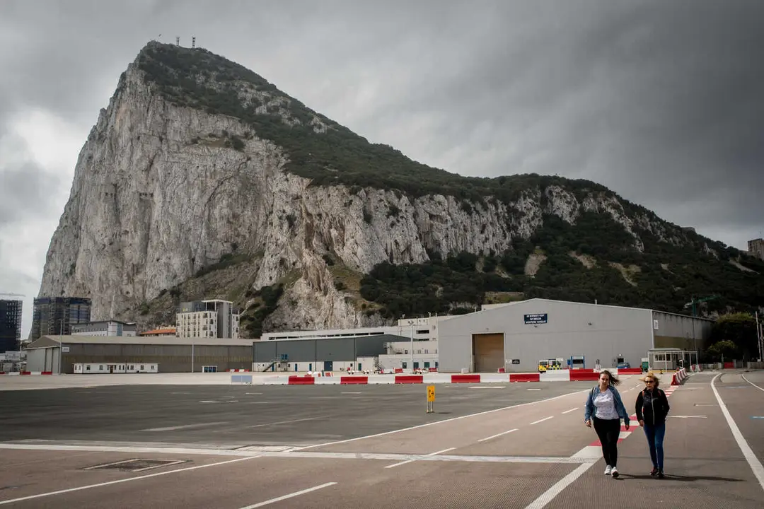 Pedestrians crossing  the asphalt at Gibraltar international airport  (British overseas territory)  near the border with Spain.