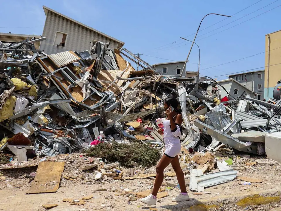 July 14, 2026, La Guaira, Venezuela: A woman walks past a collapsed building after last month�s twin earthquakes, which killed more than 4,700 people. Excavators and civil workers are carrying out controlled demolition and debris removal operations in the coastal community of Playa Grande, one of the areas hardest hit by the earthquake that struck northern Venezuela 20 days earlier. The operations have entered the recovery phase, focusing on clearing major roads blocked by collapsed residential buildings to restore access and mobility for residents as reconstruction efforts continue. (Credit Image: � Mario Flores/JNA via ZUMA Press Wire)